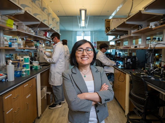 A women in a gray suit takes a photo in a science lab