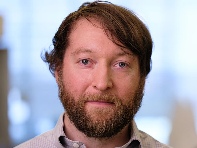 person with short brown hair and beard,wearing shirt