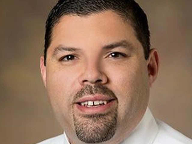 person with short dark hair and beard, wearing white shirt