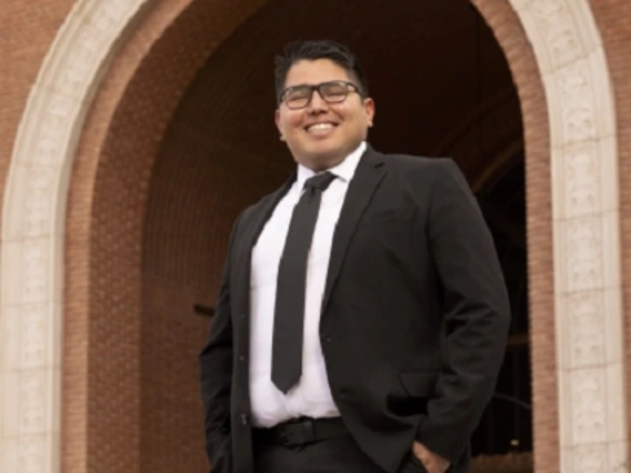 person in suit, wearing glasses, smiling