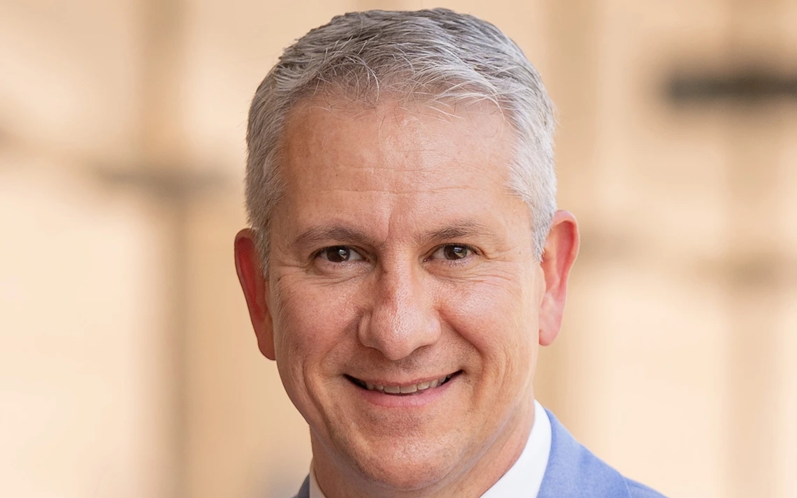 A man with gray hair smiles at the camera.