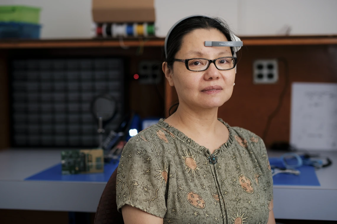 A woman with dark hair wears tech on her forehead.