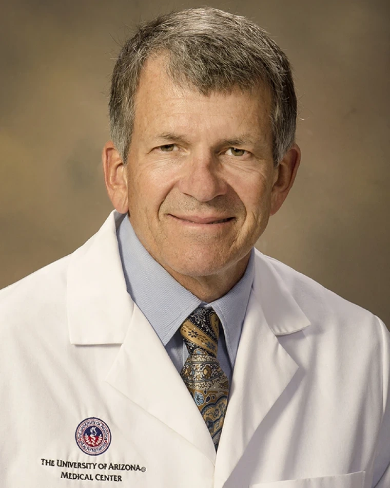 person with short gray hair, wearing white lab coat and tie