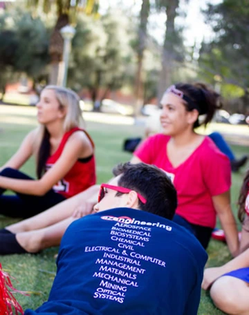 three students at an event, wearing red and blue t-shirts