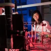 A woman in a white lab coat inside a lab with red lighting.